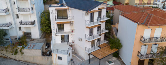 Viento Luxury Apartments - מבט אווירי של שכונת מגורים הכוללת בניין לבן מודרני רב קומות עם מרפסות. הגג בצבע אפור כהה, בניגוד למבנים סמוכים. הסביבה פרברי עם תערובת של מבנים ישנים וחדשים יותר.